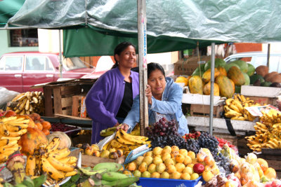 Two friendly vendors selling fruit at the market.