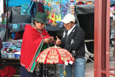 A woman buying jewelry from a vendor at the market.