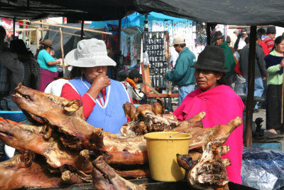 Indian vendors with pig carcasses for sale at the Guamote Market.