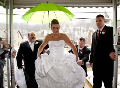 Dad shelters daughter bride from rain.