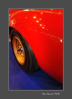 Golden rim of a red Lamborghini on a blue carpet