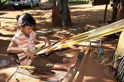 A small Kreung orphan, weaving to support her grandmother in Krase, Cambodia.