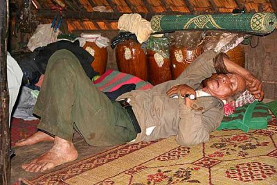 Phnong man taking a nap next to his jars with rice wine. Pu Tang village, Mondulkiri, Cambodia