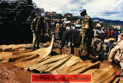 Views from within the Zambian Company of the United Nations Assistance Mission for Rwanda (UNAMIR) at about 14:30 on Tuesday, 18 April 1995. Note the relative calm, despite great pressure around the camp, which, in some places has broken down razor-wire fencing.  Note also the high proportion of adult and adolescent males and attempts being made to identify the corpses of those killed in an earlier crush.  The Zambian captian is holding a pistol (apparently concerned about the possibility of his base being run-over in another outbreak of disorder).