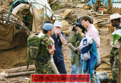 With Captain Shema of the RPA looking on and a UN visitor from New York shielding his nose from the smell of decaying bodies in the vicinity, Major Mark Cuthbert-Brown is interviewed by Ben Brown of the BBC about events including summary executions that he had witnessed 5 days earlier.  This and other interviews concerning the breakdown of Kibeho were seen around the globe that evening and in following days.  (Taken by John Cleland with the camera of Mark Cuthbert-Brown.)