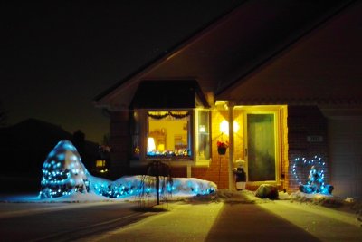 Winter LED landscape lights contrast with the warmth of a cozy scene.