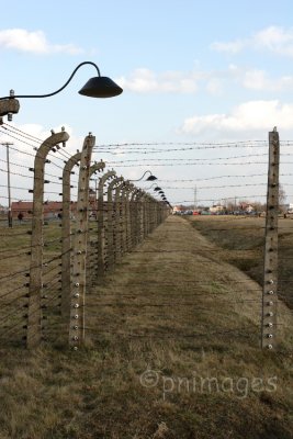 Electric Fence with Hells Gate behind,   Birkenau,   Poland.