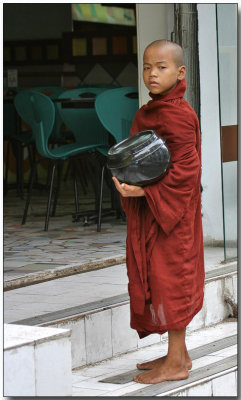 Novice monk with alms bowl waiting for breakfast