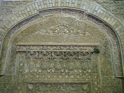 an exquisite stucco mihrab awash with dense Quranic inscriptions and foral designs