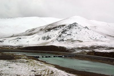 A small bridge across the river with the Tibet Highway on the opposite bank