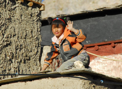 A young girl waves from her rooftop perch