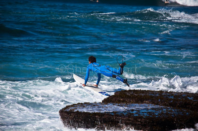 Surfer jumping from rocks at Avalon