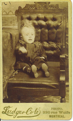 If you look closely you will see what looks like a box under the child's cloths.
I believe that he has passed as this photos came with many other postmortem photos.
His hand may have fallen during the photo process.
The photo is by one of Montreal premier photographers for this type of photo( postmortem).
I have had many comment on this image and I am now perplexed is he alive or has he left his body?

