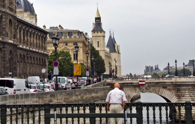 An old man looking at the traffic by the Seine river