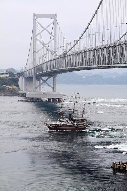 Old-style boat passing under the bridge