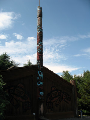 Totem pole above a replica Tlingit house