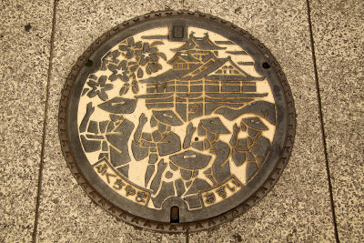Manhole cover depicting traditional festivities