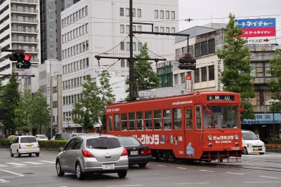 Traffic passing a bright red roman-densha