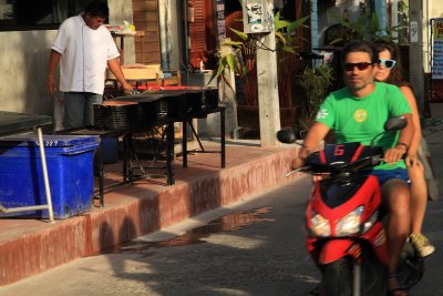 Couple riding past an outdoor grill, Bo Phut