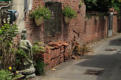 Buddhist statue along a brick-walled lane