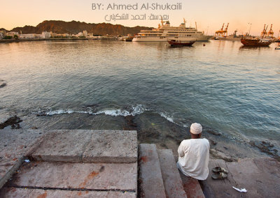 Man sitting next to Sultan Qaboos Port in Mutrah