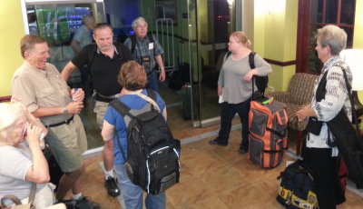Larry, Paul and Mary share a laugh while waiting for the airport shuttle. Jerry, Sarah and Gail wait with their bags.