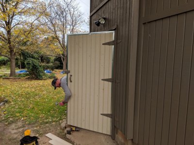 Jesse nailed down the metal trim on the sides of the newly-paneled shed door so it would close smoothly.