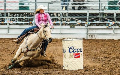 Barrel Racing competitor steers her horse around a barrel