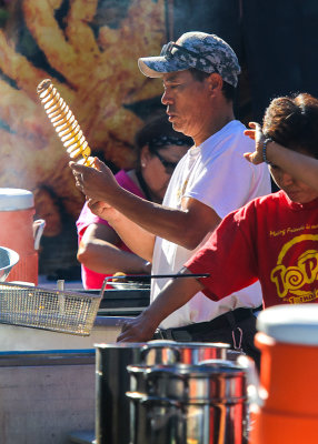 Preparing deep fried potato spiral on a skewer at the 4th Avenue Street Fair
