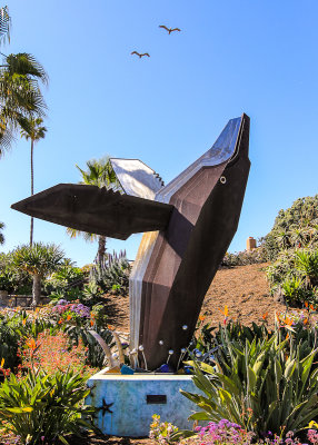 Birds flying over the breaching whale statue in Laguna Beach