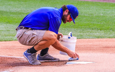 A member of the ground crew prepares home plate at Wrigley Field