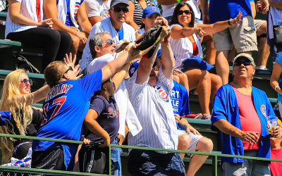 Fans reach for a ball hit into the left field bleachers at Wrigley Field