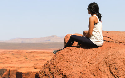 Woman on the edge of a cliff at Horseshoe Bend in Glen Canyon NRA