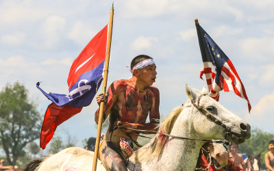Indian Nation warriors ride off with the U.S. Cavalry flags at the Battle of the Little Bighorn