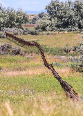 Length of barbed wire fence stretches through a field in Minidoka National Historic Site