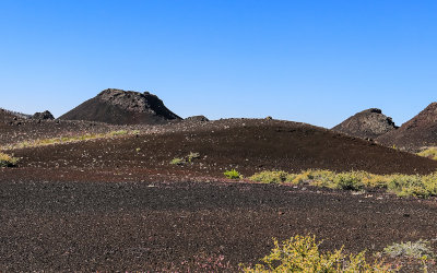 Spatter Cones viewed beyond a hill of cinders in Craters of the Moon National Monument