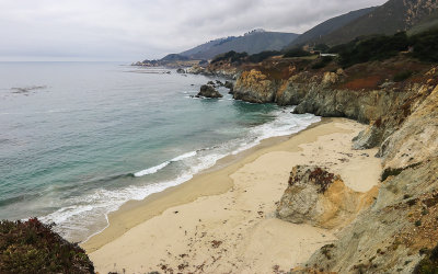 View of a sandy beach and the rugged coastline near the Rocky Creek Bridge along California Highway 1