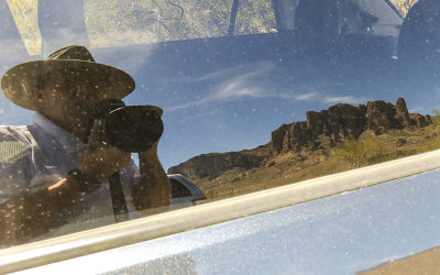 Self-portrait with the Superstition Mountains reflected in a car window