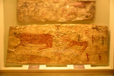 This mural depicts a deer and wild boar hunt. People holding bows and arrows in their hands are depicted in red and black paint