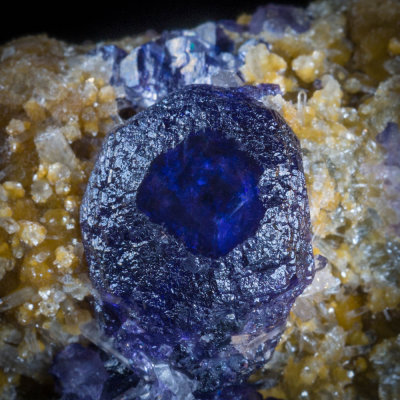 Smooth blue cube face surrounded by stepped hexoctahedral faces, fluorite crystals on quartz