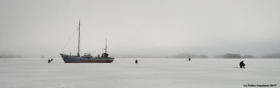 Ice fishing by the rusting ship