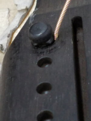 Grooving bridge pin holes to allow for string using solid bridge pins.