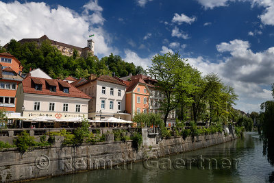 Bright pastel colors of renovated historic buildings Cankar Quay embankment of the Ljubljanica river canal and Castle Hill of Lj