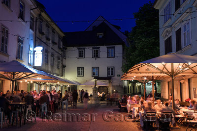 Nightlife outdoor restaurant cafes in Cobblestone Courtyard Ribji or Fish Square from Cankar Quay to Town Square in Old Town Lju