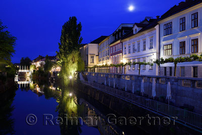 Cobblers Bridge and houses reflected on the calm Ljubljanica river canal in moonlight at dawn in Ljubljana Slovenia