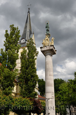 Clock and bell tower of St James parish Catholic church and St. Marys Column of the virgin in brass and stone statues of saints