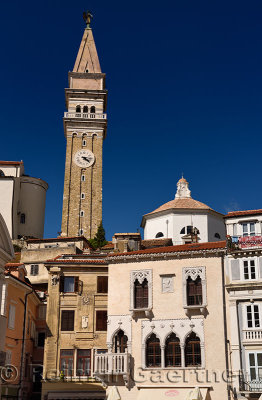 Bell and clock tower of St Georges Parish Catholic Cathedral and baptistery with pink Venetian House in Tartini Square Piran Sl