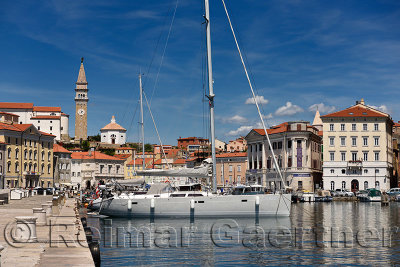 Yachts and boats in the inner harbor of Piran Slovenia with Cathedral, belfry and baptistery of St Georges church