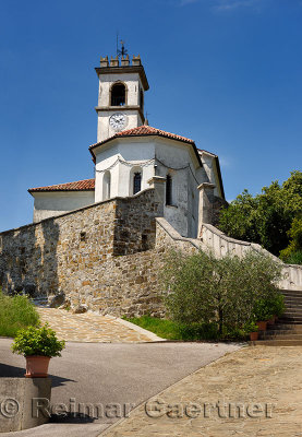 White catholic church of Saint Leonard with chain and clock belfry in Dolnje Cerovo Gorica Hills Brda Slovenia