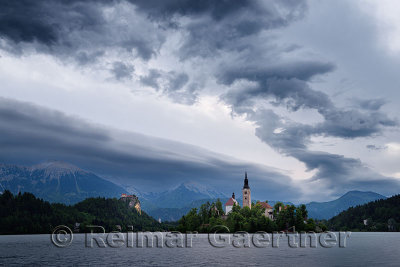 Clouds over Stol and Begunjscica peaks Karawanks mountains over Lake Bled at dawn with Assumption of Mary church on Island and B